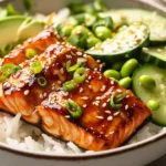 Honey garlic salmon bowls with rice, avocado, cucumber, and sesame seeds in a cozy evening kitchen
