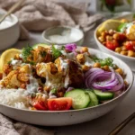 Cauliflower shawarma bowls with roasted cauliflower, rice, chickpeas, cucumbers, tomatoes, herbs, and creamy tahini sauce.