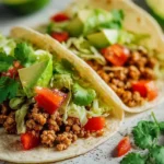 Ground turkey tacos with avocado, lettuce, and lime on a softly lit kitchen counter