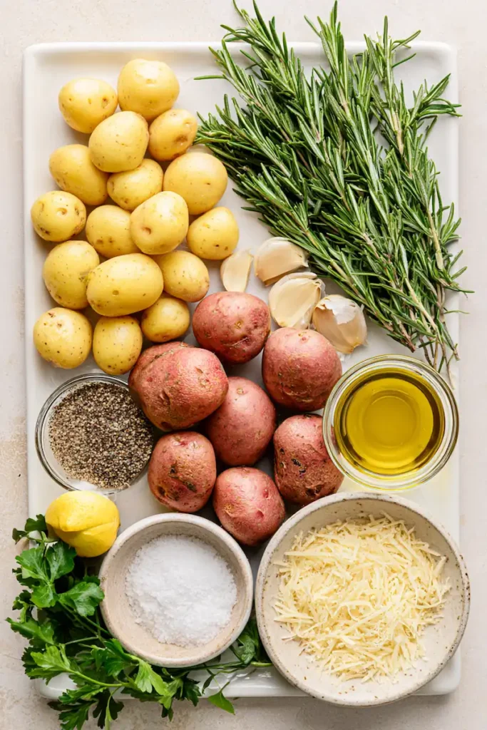 Rosemary Roasted Baby Potatoes 3 Baby potatoes, rosemary, garlic, Parmesan, and olive oil arranged on a white kitchen counter