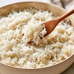 Soft long-grain white rice being fluffed in a saucepan for a guide about preventing mushy rice.
